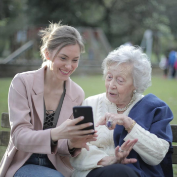 Millennial aged female helping an older adult with a smartphone 