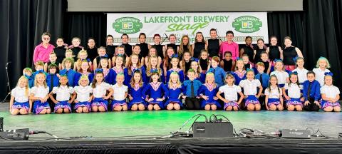 Group of Cashel Irish Academy dancers sit and stand in rows after a competition.