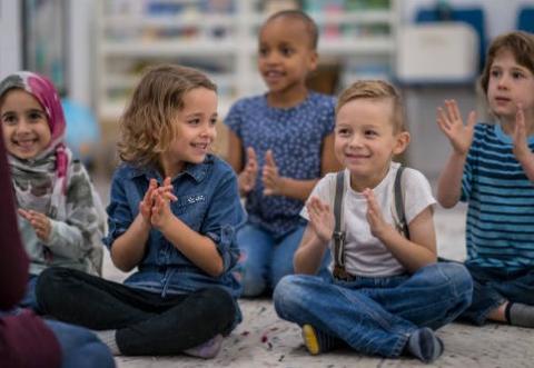 children seated with hands clappling