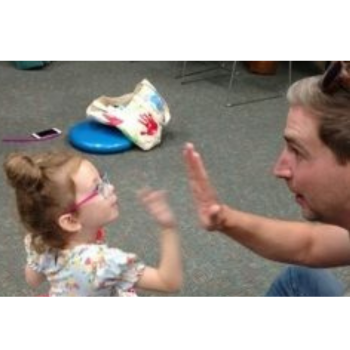 Adult and child giving high-fives while sitting on the floor