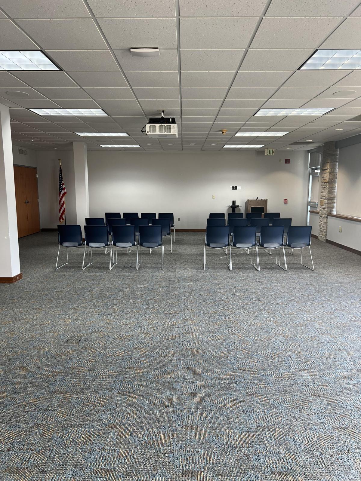 Large meeting room with rows of chairs, projector, and screen.